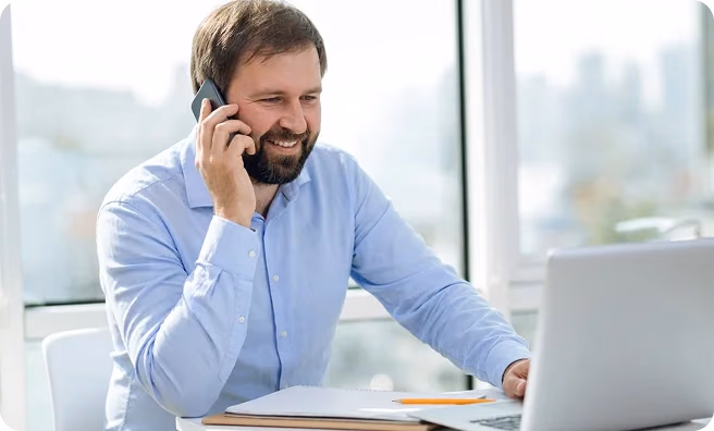 Telefonat am Arbeitsplatz mit geöffnetem Laptop.